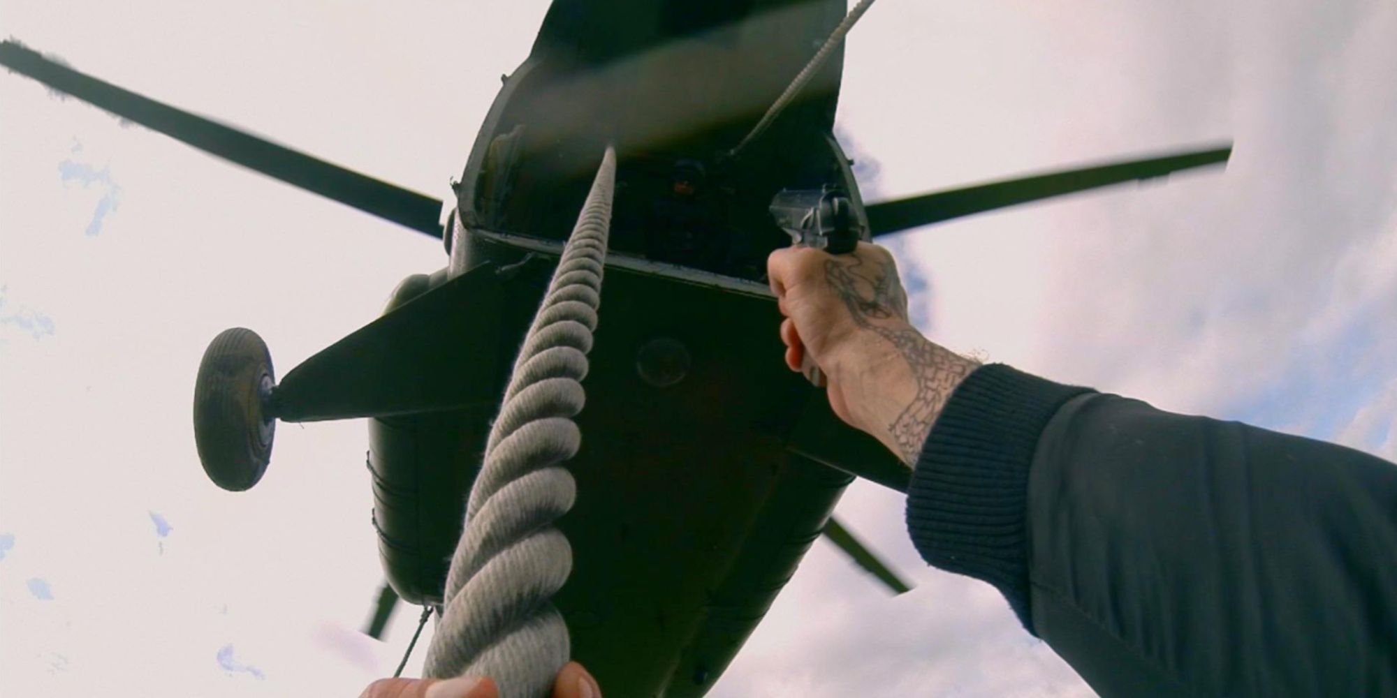First-person shot of Henry climbing the rope dangling from a helicopter while shooting at an enemy inside.