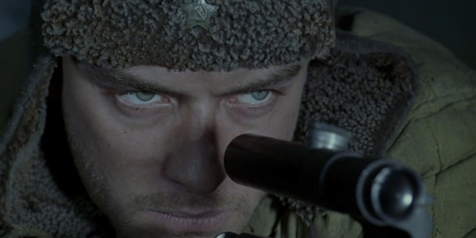 Close-up of Jude Law's character Vassili aiming down the scope of his sniper rifle at an enemy.