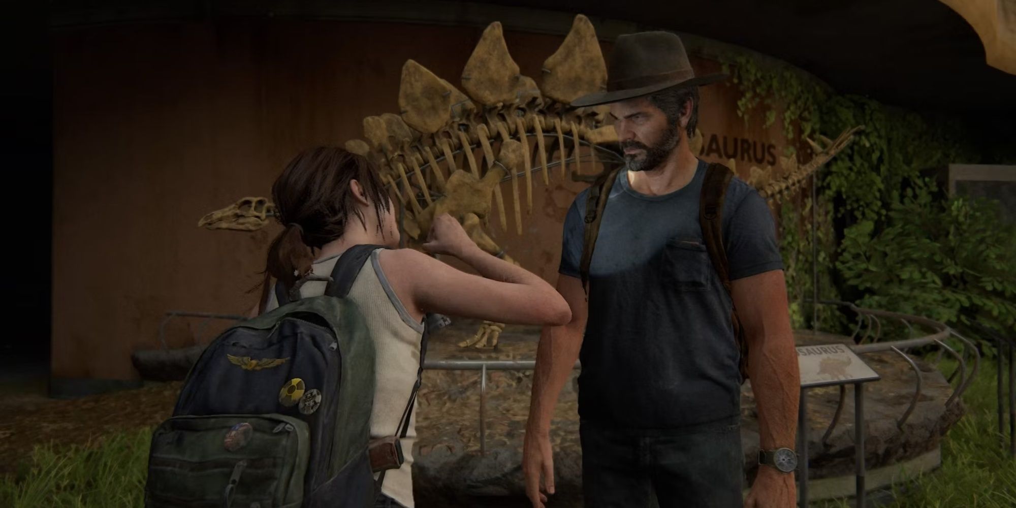 Ellie taking a picture of Joel in a cowboy hat in front of a large skeleton of a Stegosaurus.