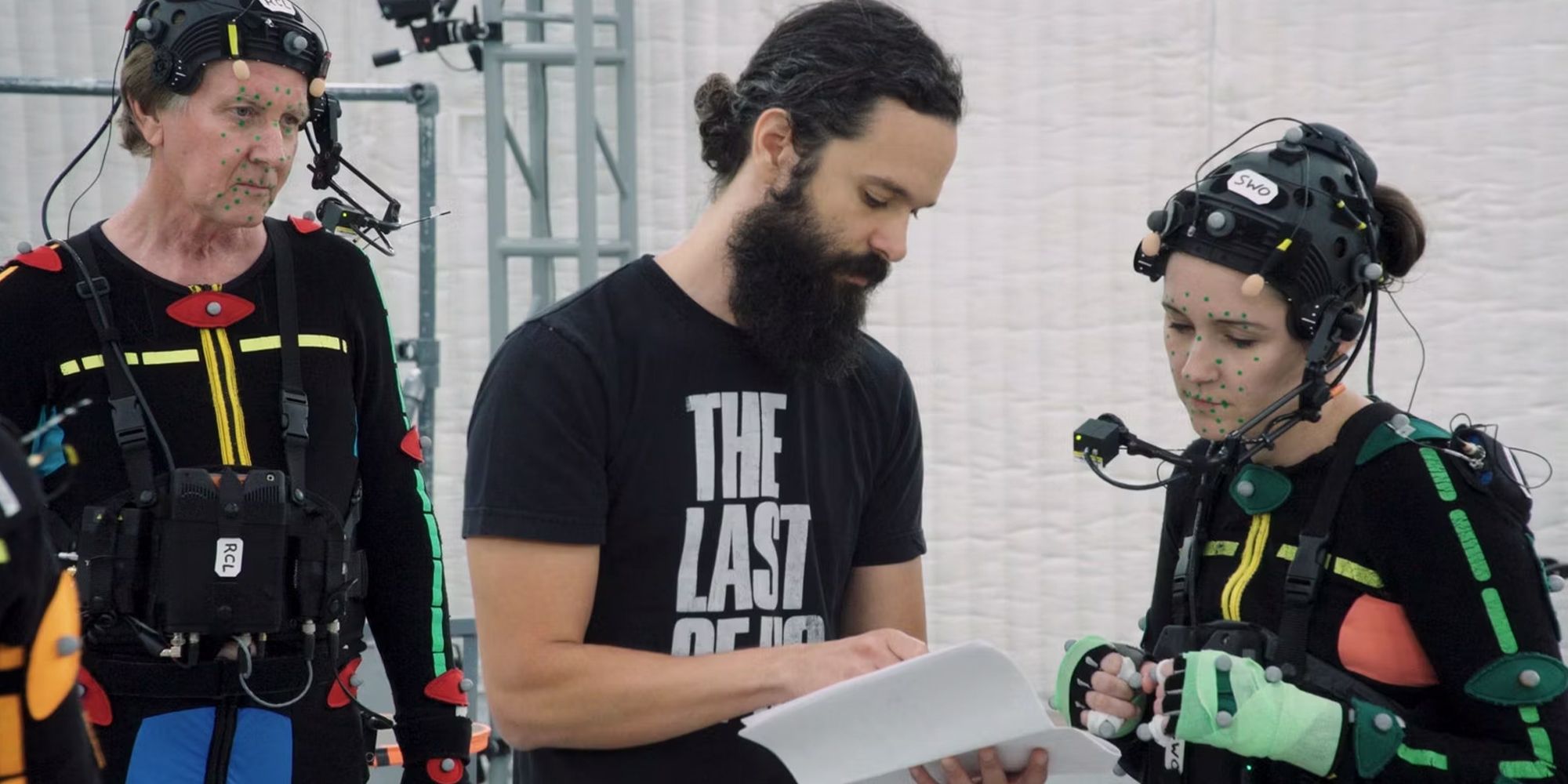 Neil Druckmann on the set of The Last of Us Part 2 with two actors in mocap suits, reading a script
