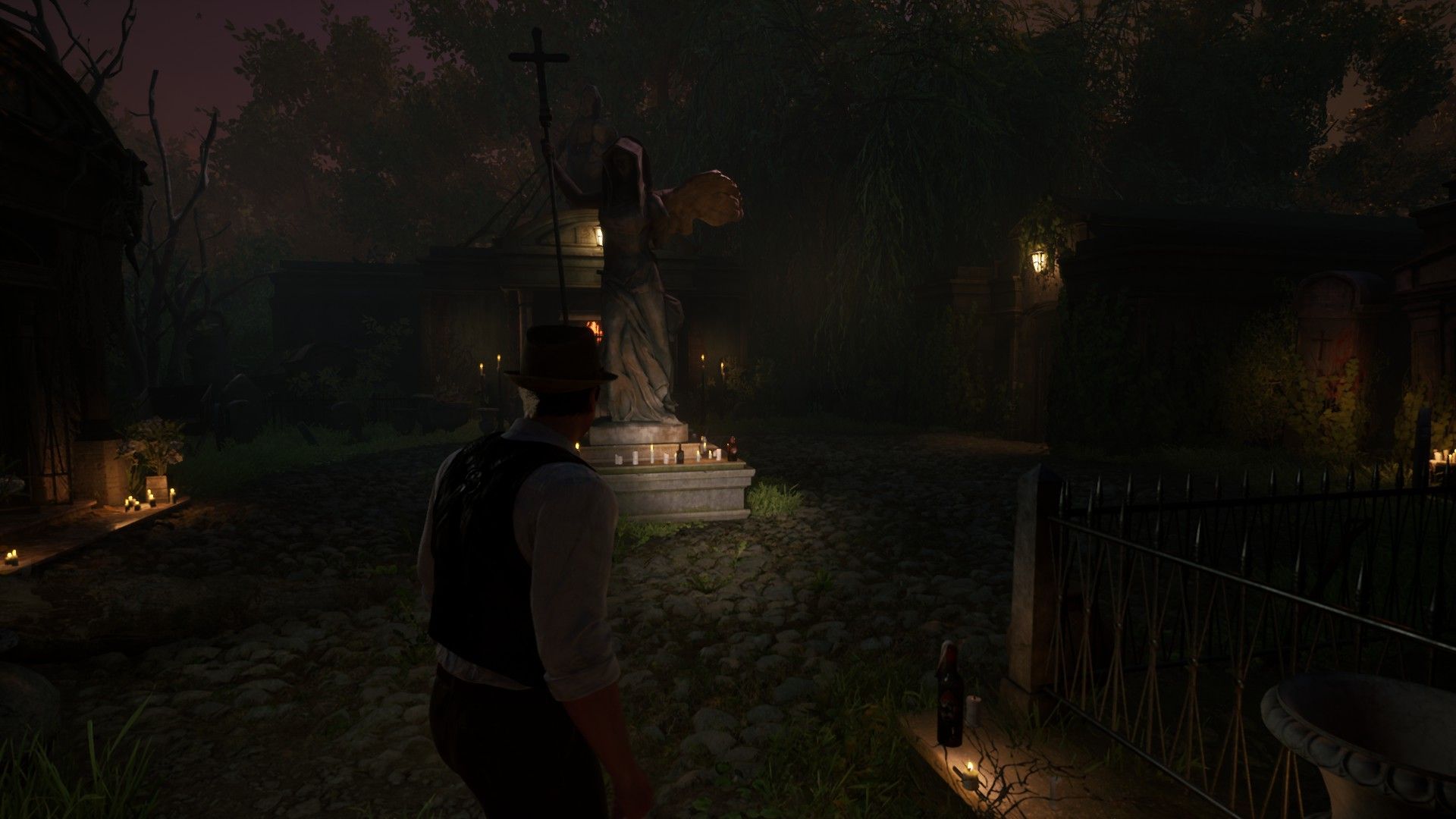 Edward in the cemetery beside a statue of an angel in Alone in the Dark.