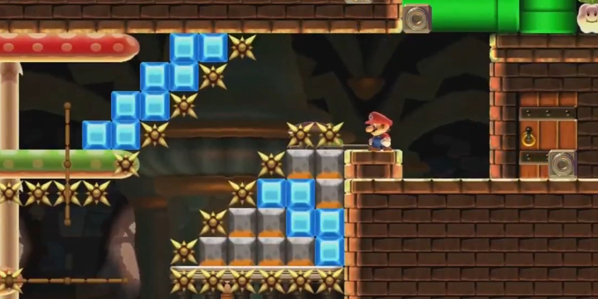 Mario standing at the end of a brutal level filled with spikes, platforms, and bombs
