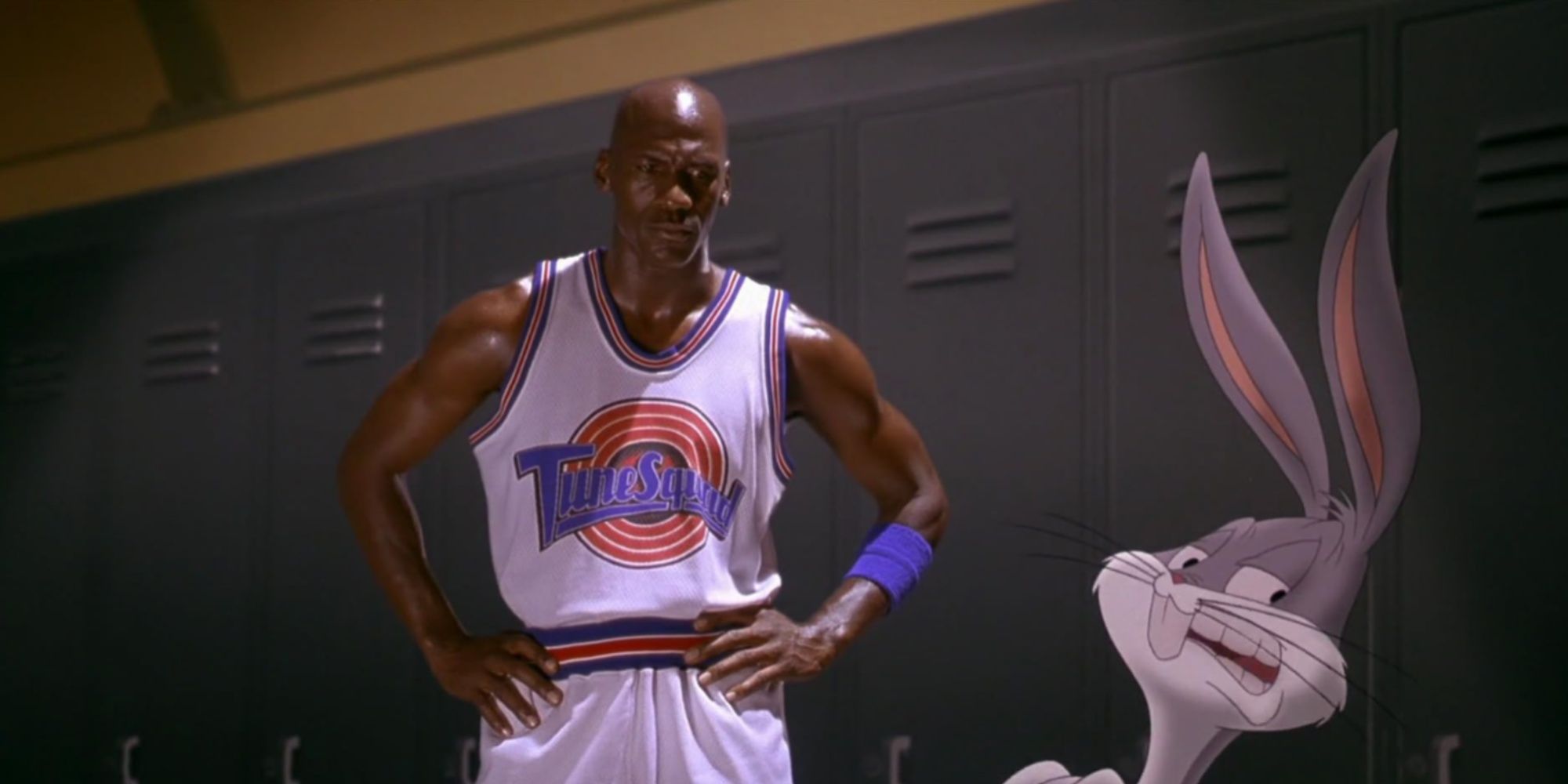 Michael Jordan in his TuneSquad uniform with his arms on his hips looking over at Bugs Bunny in the locker room.