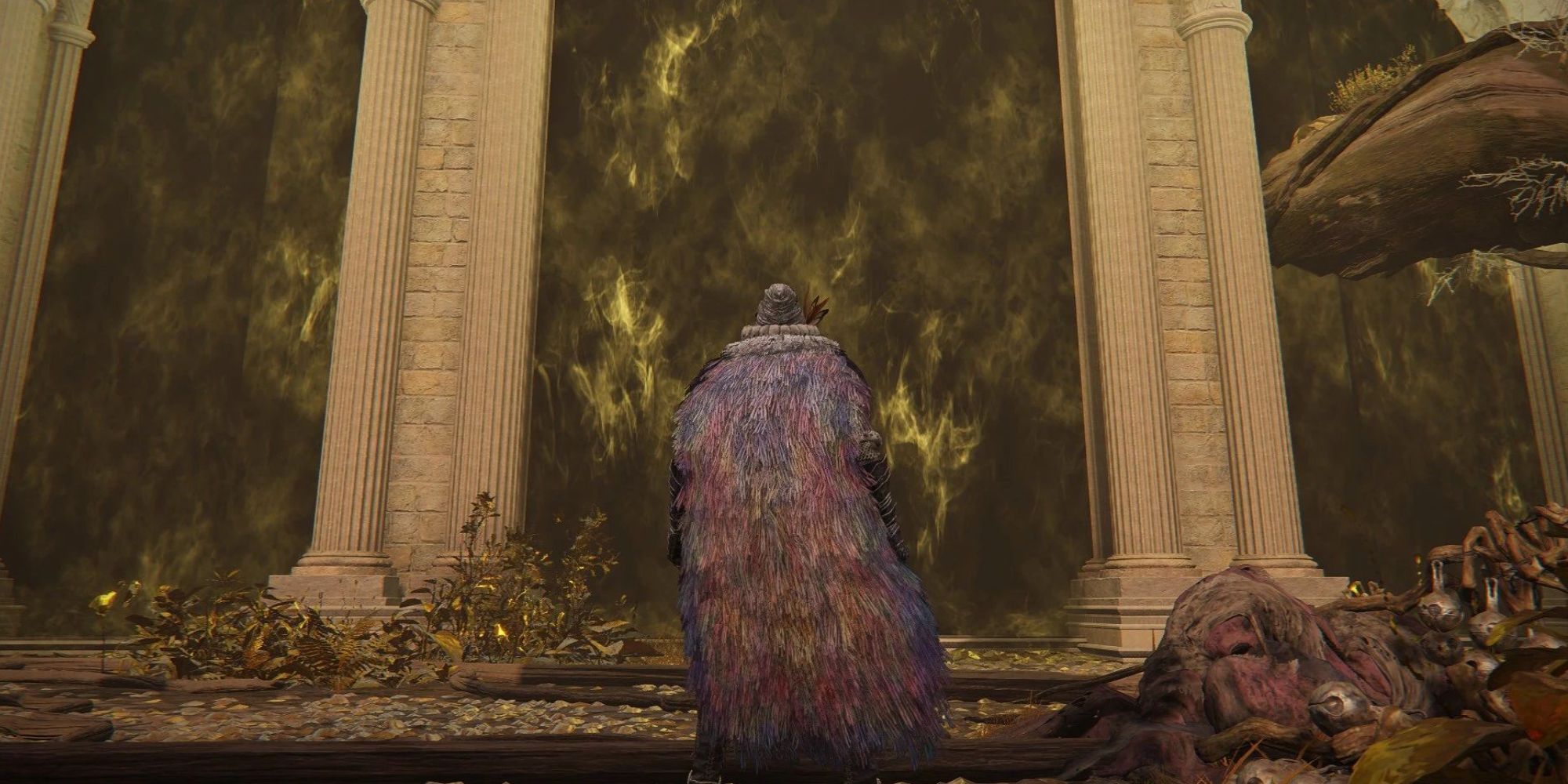 A man stands in front of the fog gate, which reaches up into the sky boarded by pillars