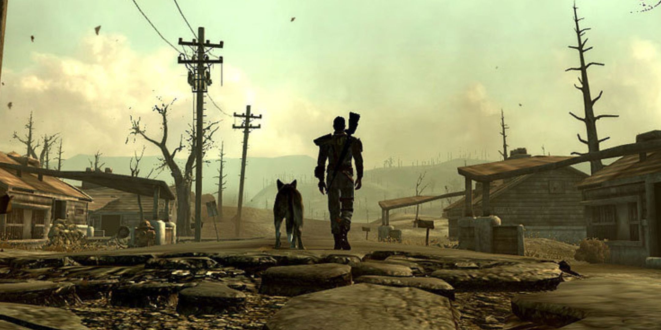 Fallout 3 protagonist and Dogmeat on a broekn road in the middle of some houses