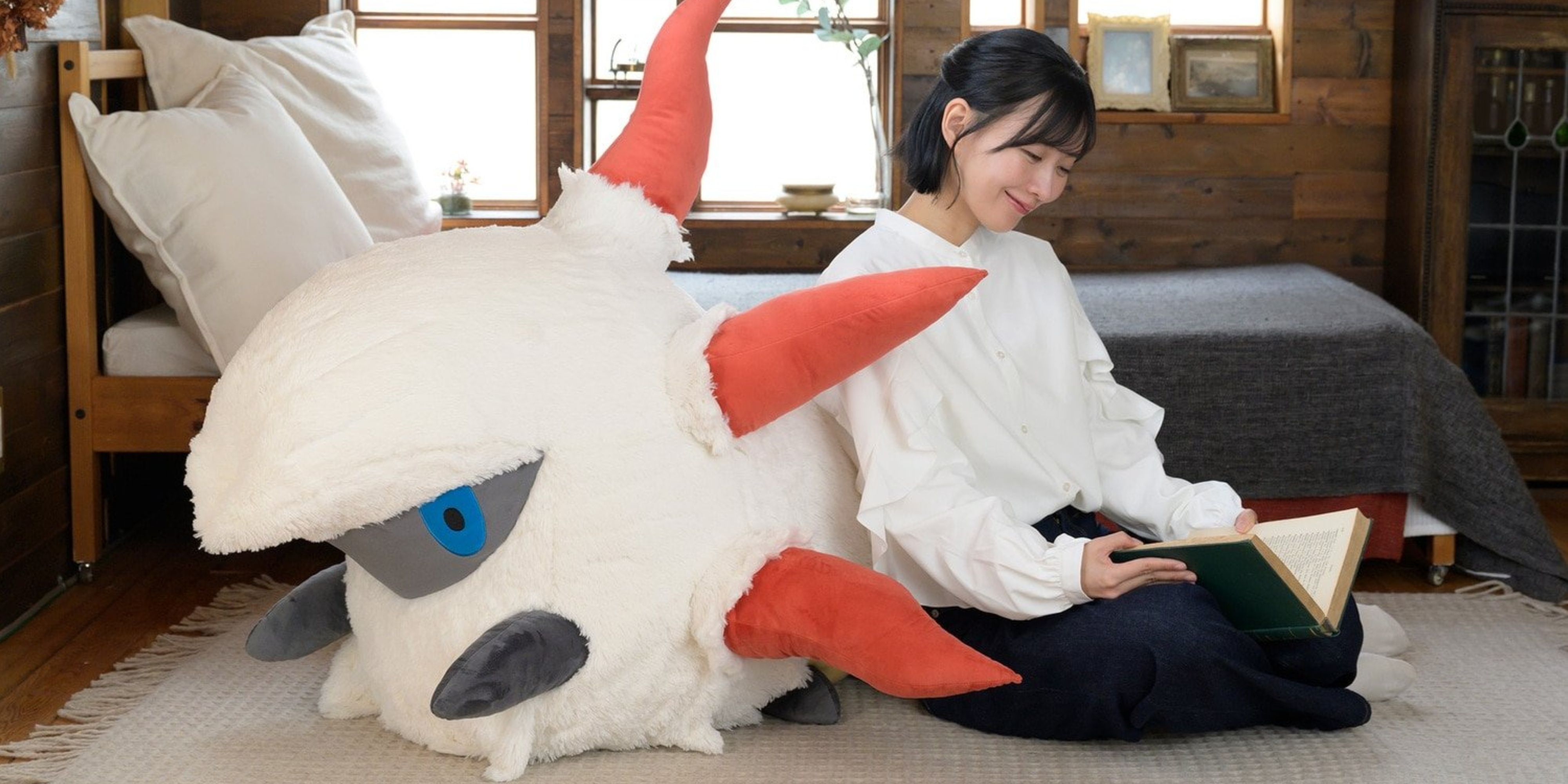 woman resting on a life-size larvesta plush while she reads a book