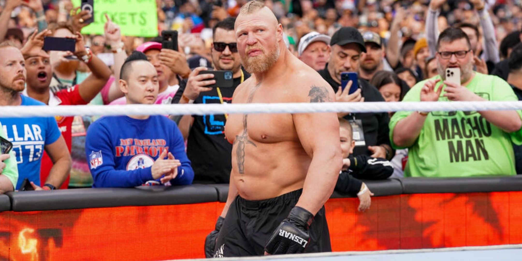 Brock Lesnar standing outside a WWE ring with fans behind him.