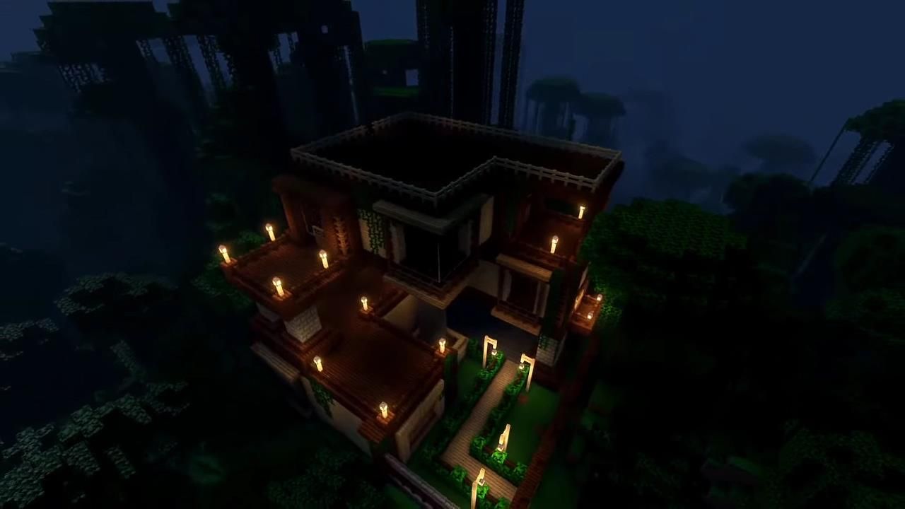 A large Minecraft jungle house lit by torches at night, with lots of square shapes and a light wooden path through some bushes leading to the front door.