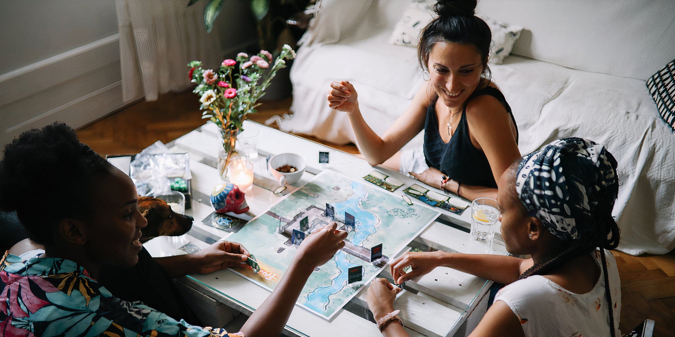 Three players at a table with a board game