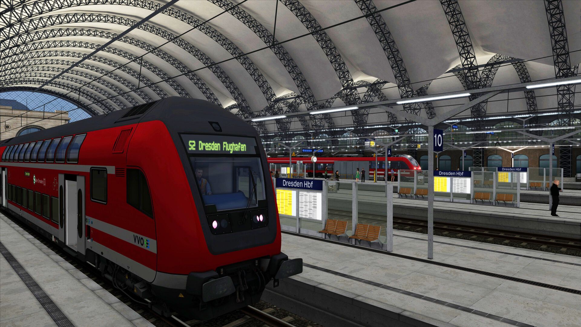 A red train is parked in an indoor train station in Europe