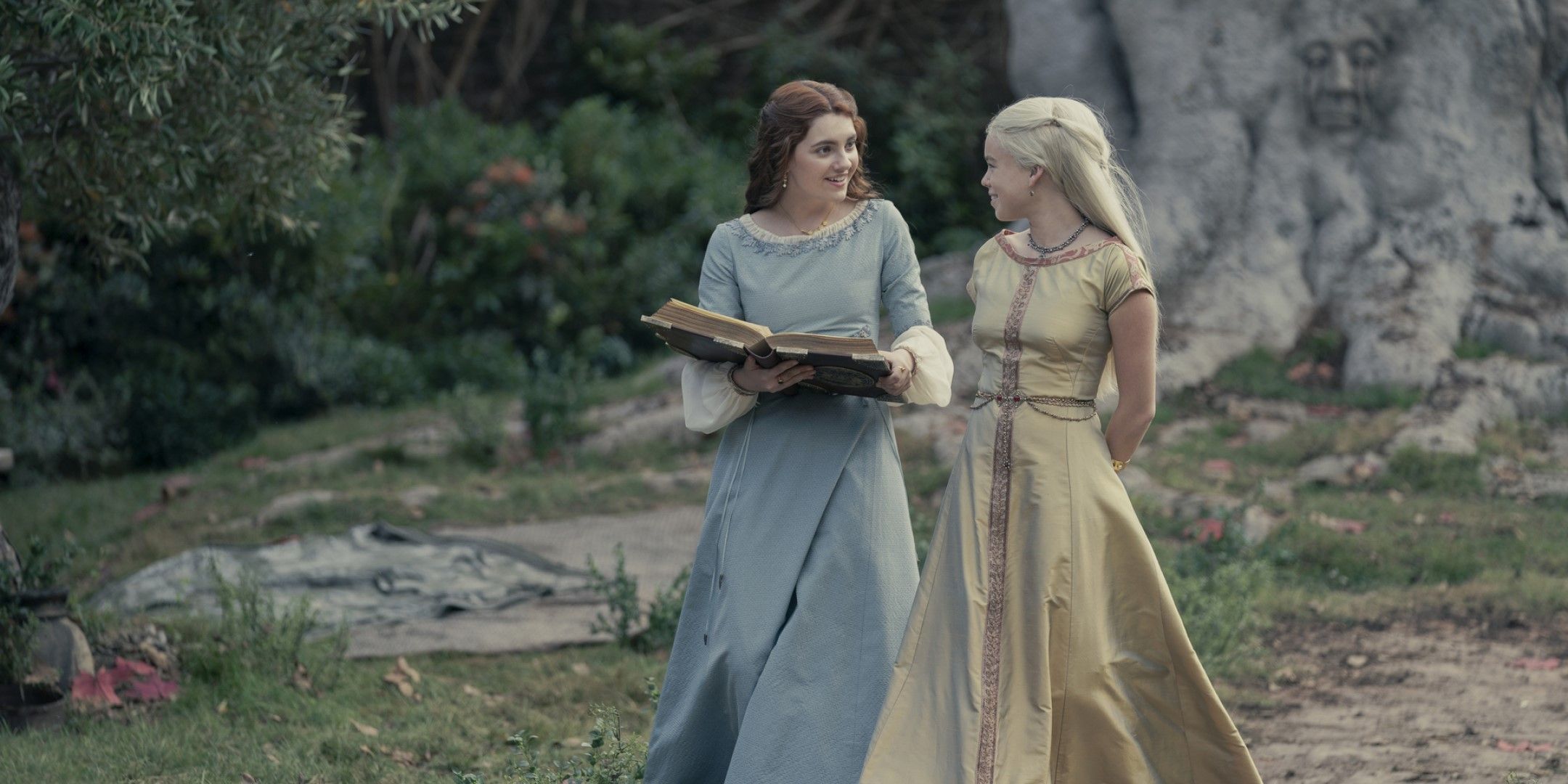 A screenshot from House of the Dragon showing Rhaenyra and Allicent walking and enjoying a book.