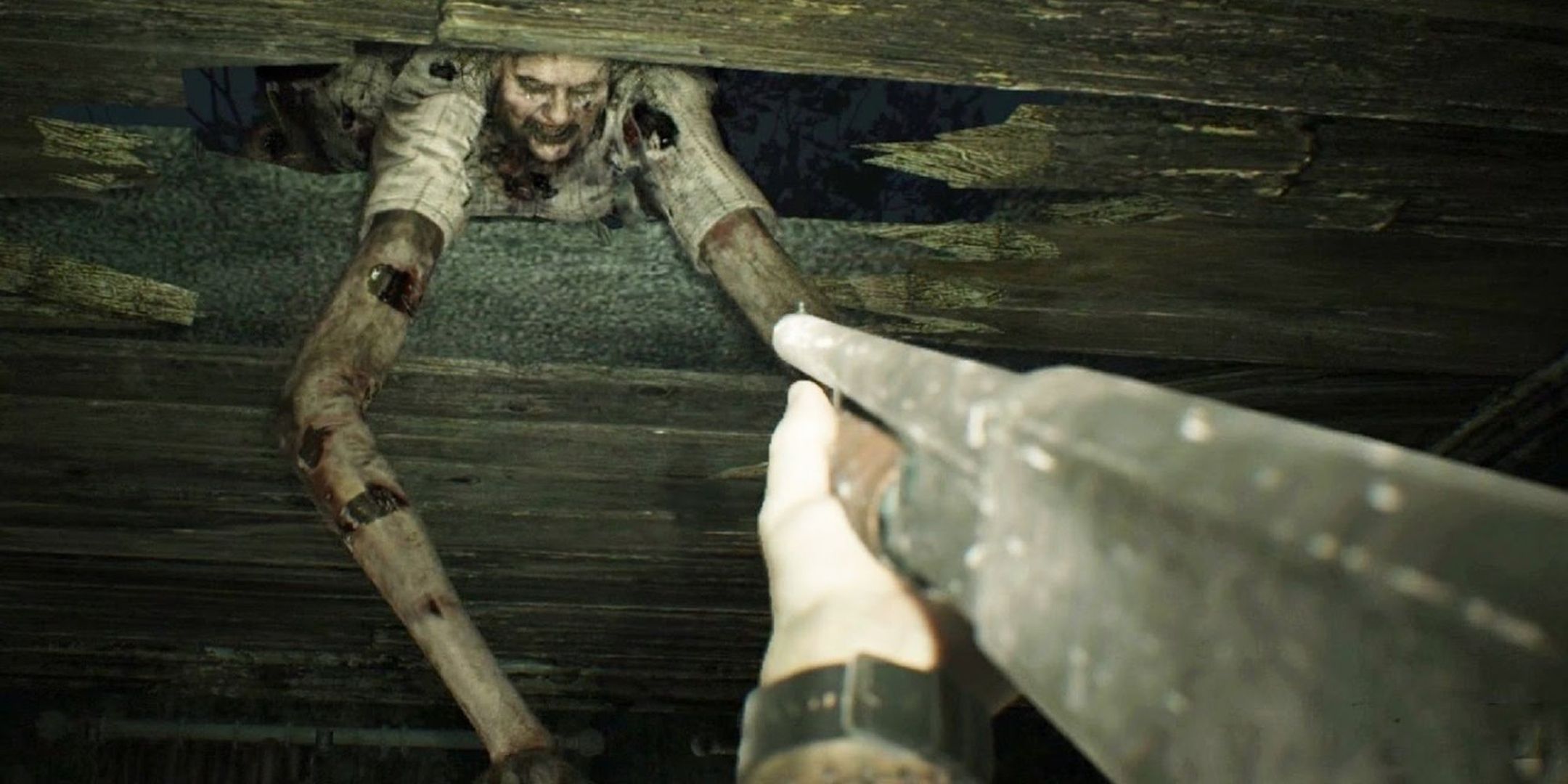 ethan winters aims a shotgun at marguerite baker as she elongates her arms to attack him through a hole in a wooden wall in resident evil 7.