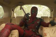 deadpool holding a knife in the back of a trashed car