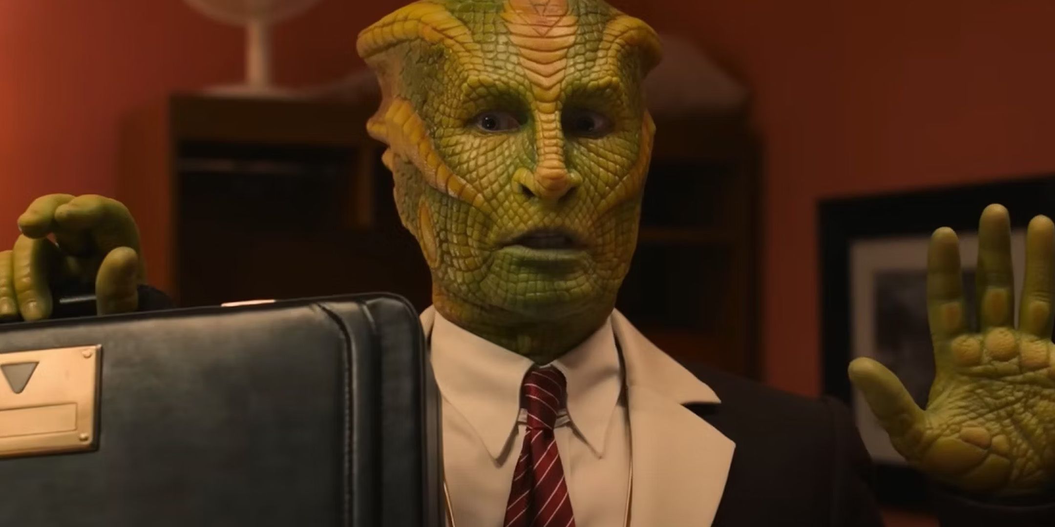 Doctor Who Joy to the World screengrab of a Silurian holding his hands up, while also holding a briefcase.