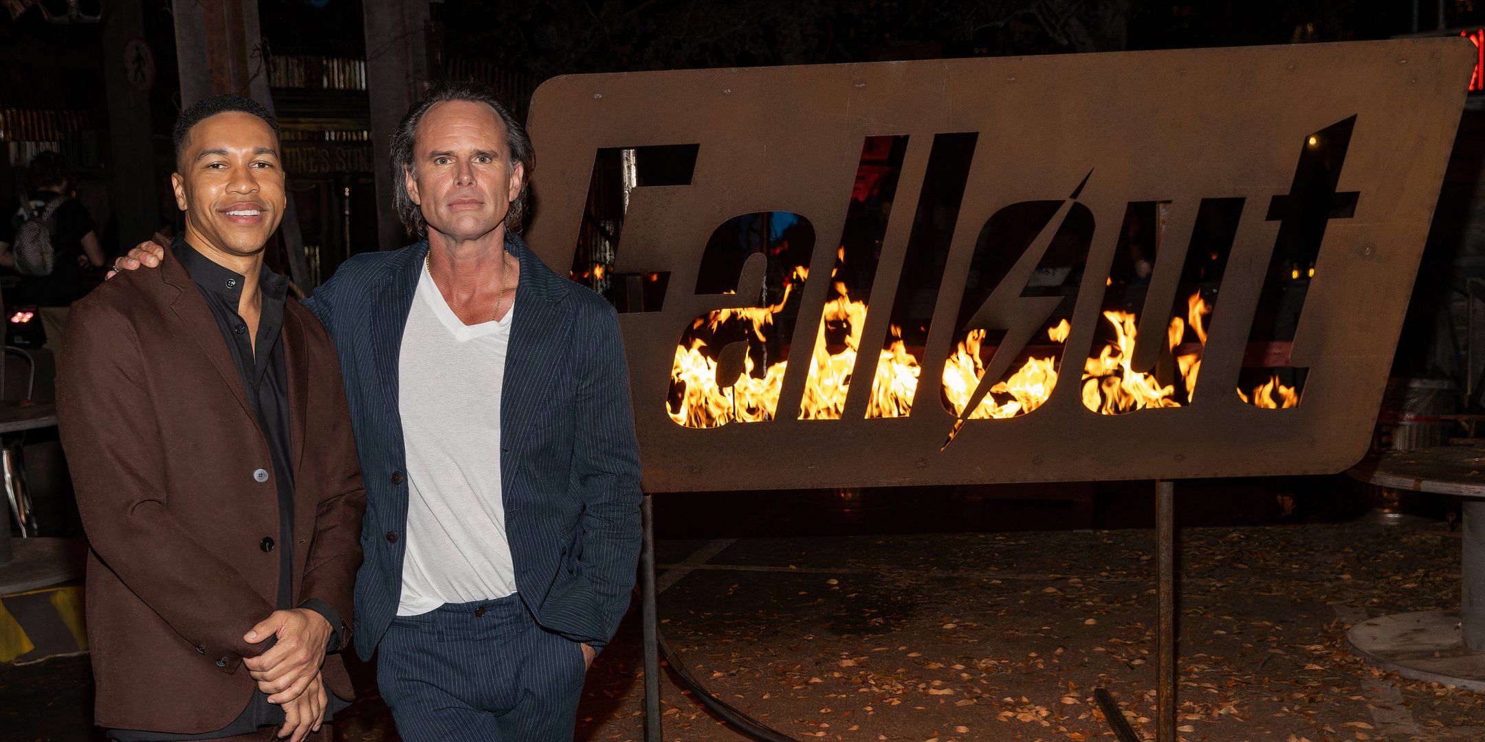 Fallout walton goggins next to flaming fallout logo