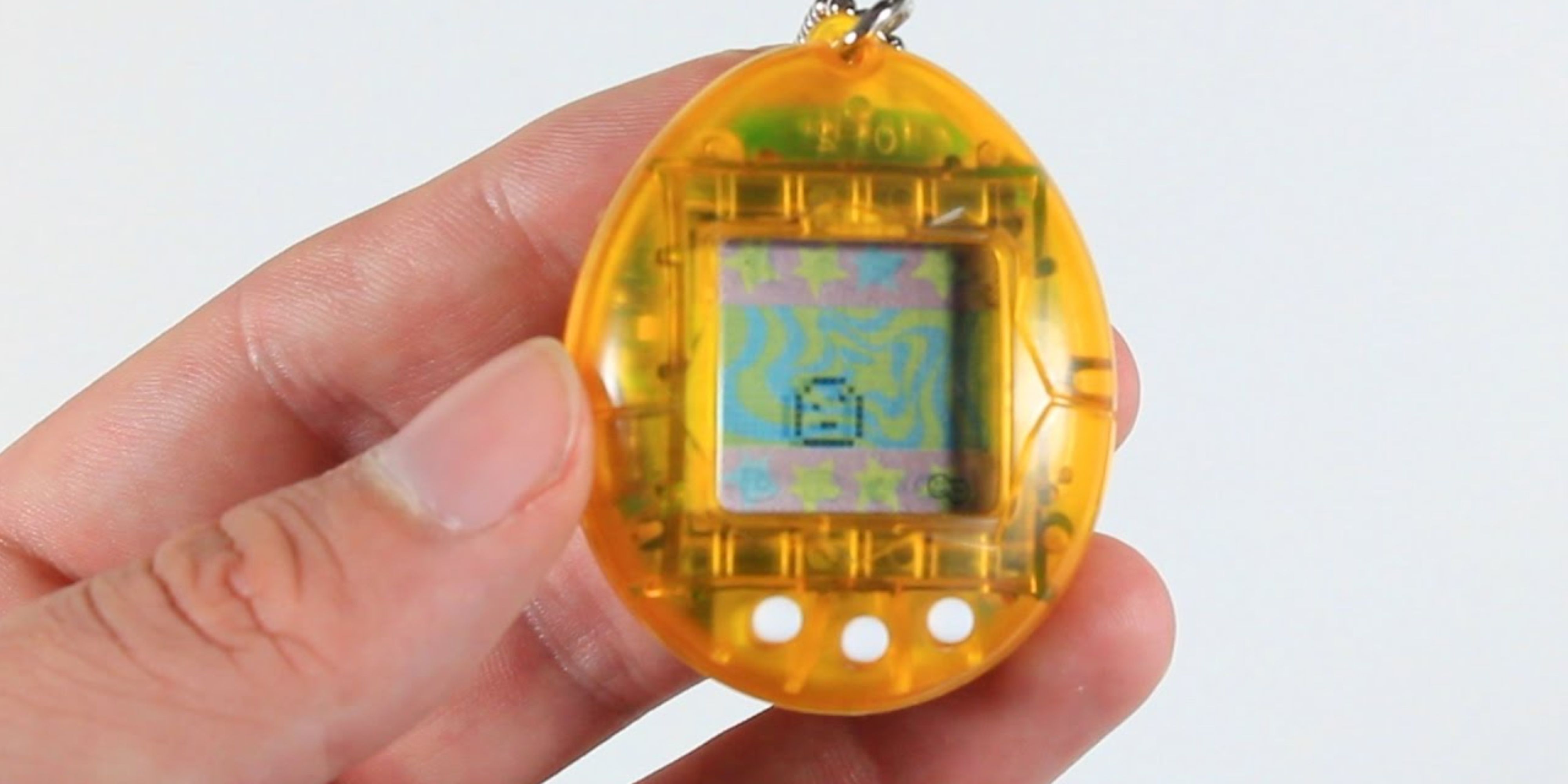 someone holding an original orange tamagotchi.