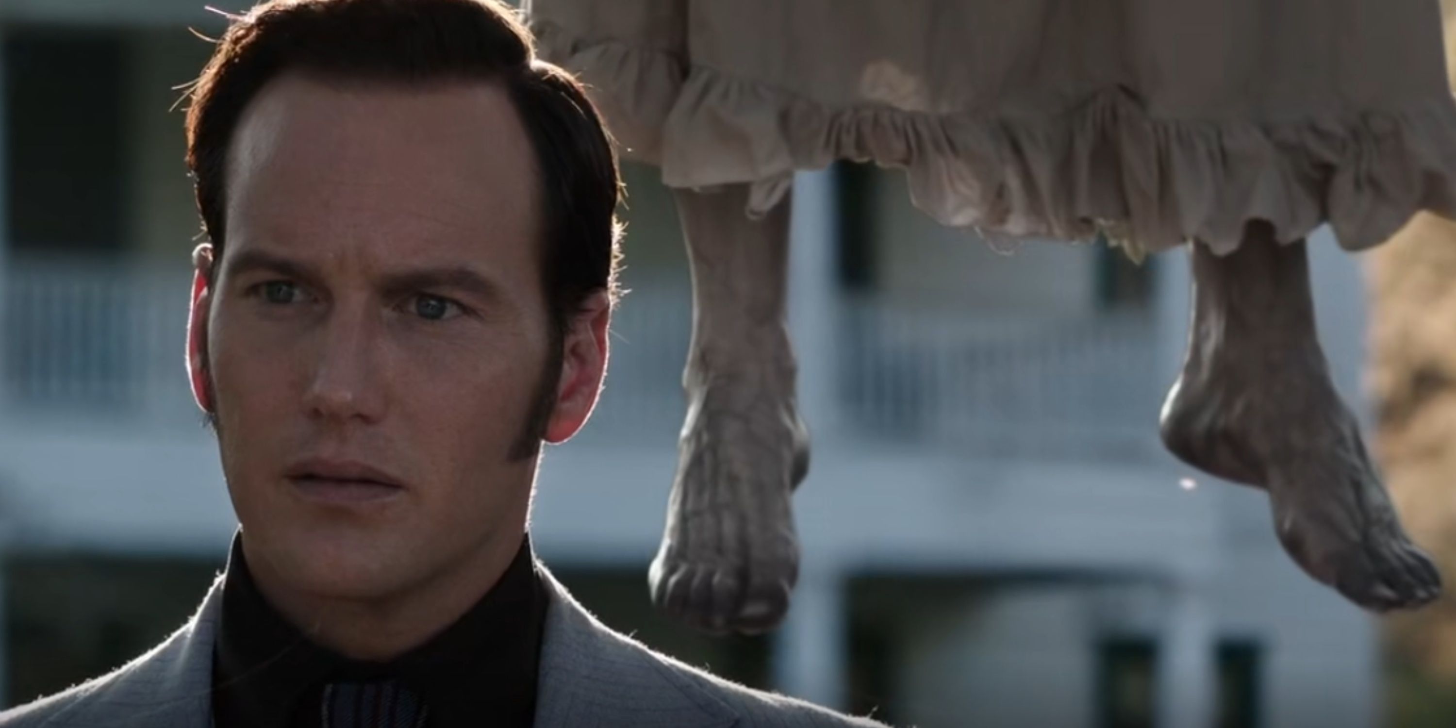 The decayed feet of a hanging ghost floats behind an unaware Ed Warren in The Conjuring.