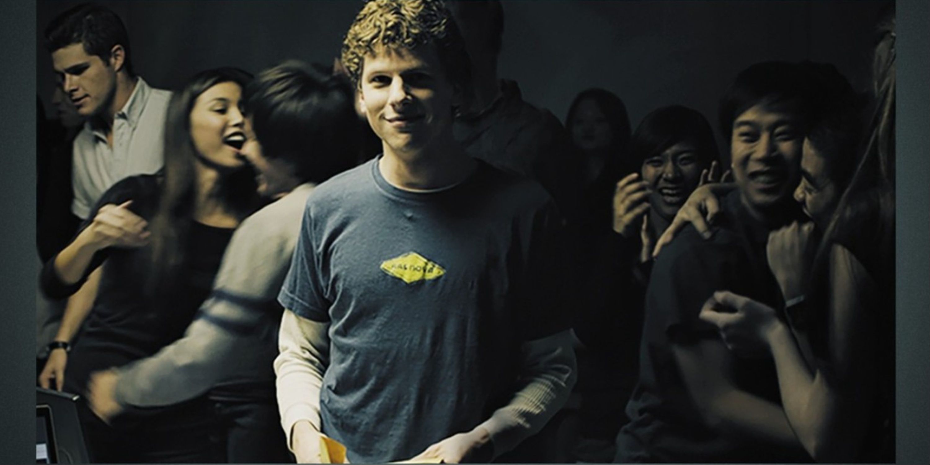Jesse Eisenberg as Mark Zuckerberg for the main art for social network with PartyGoers behind him.