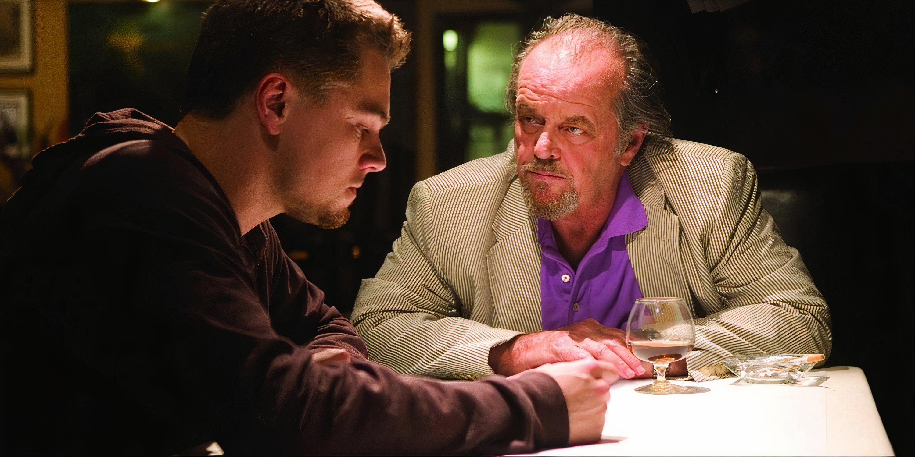 Leonardo DiCaprio and Jack Nicholson seated at a table and discussing matters in The Departed.