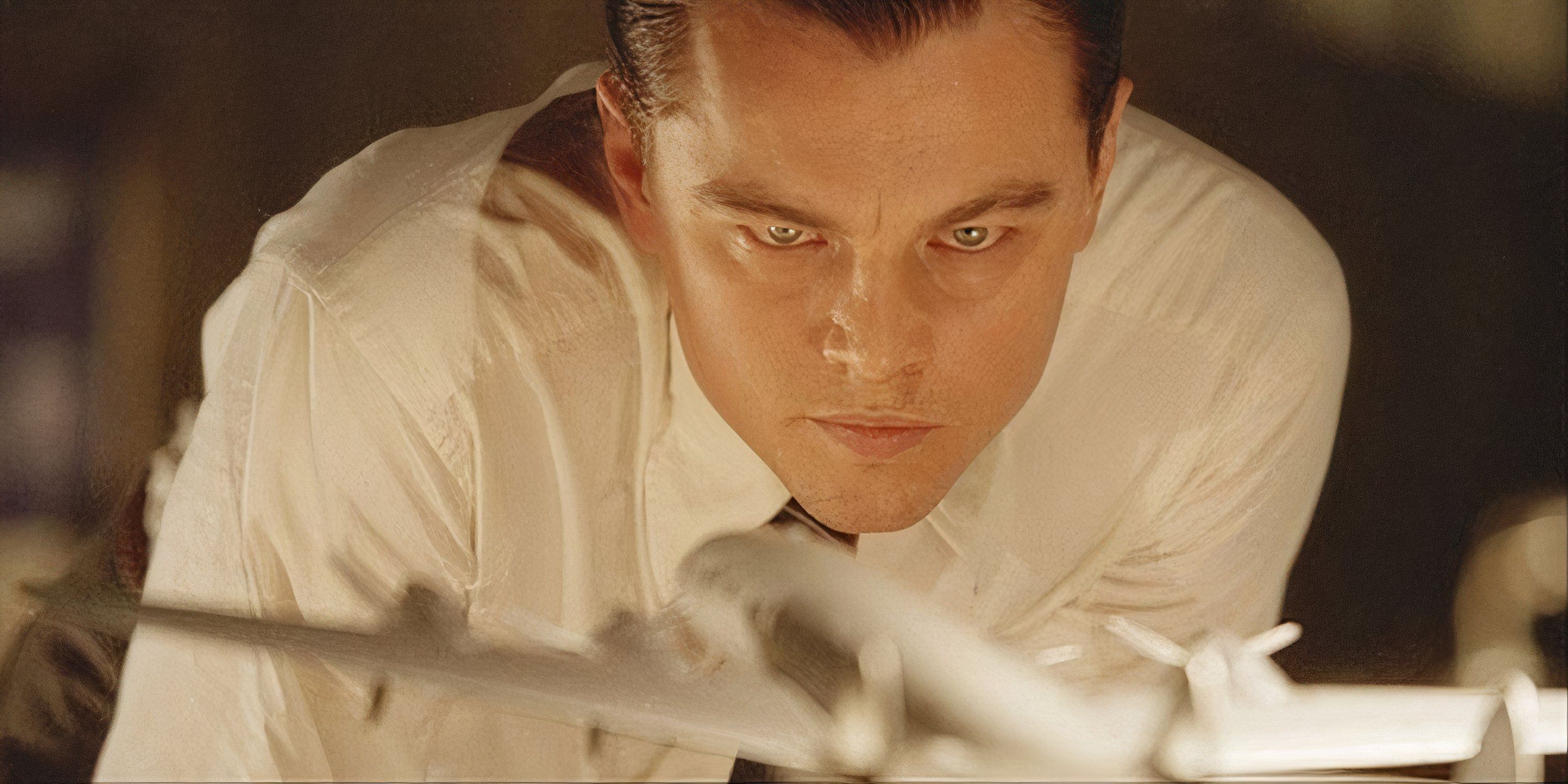 Leonardo DiCaprio as Howard Hughes staring intently at a model airplane in The Aviator.