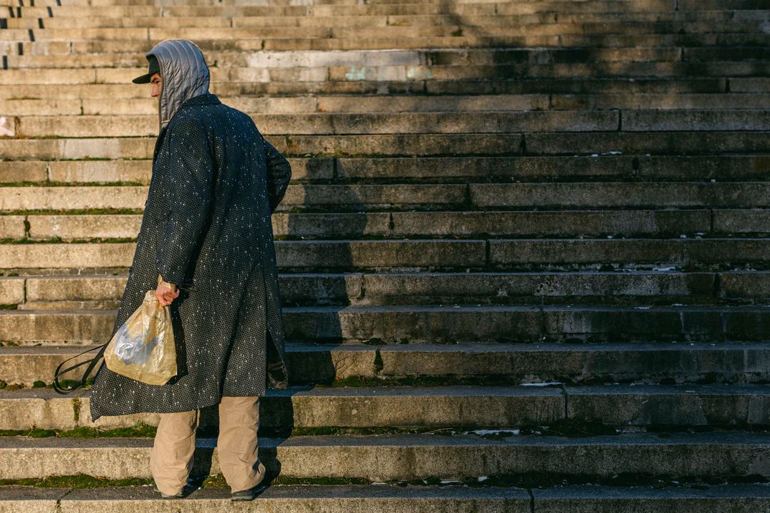 Man on some steps holding a Disco Elysium carrier bag.