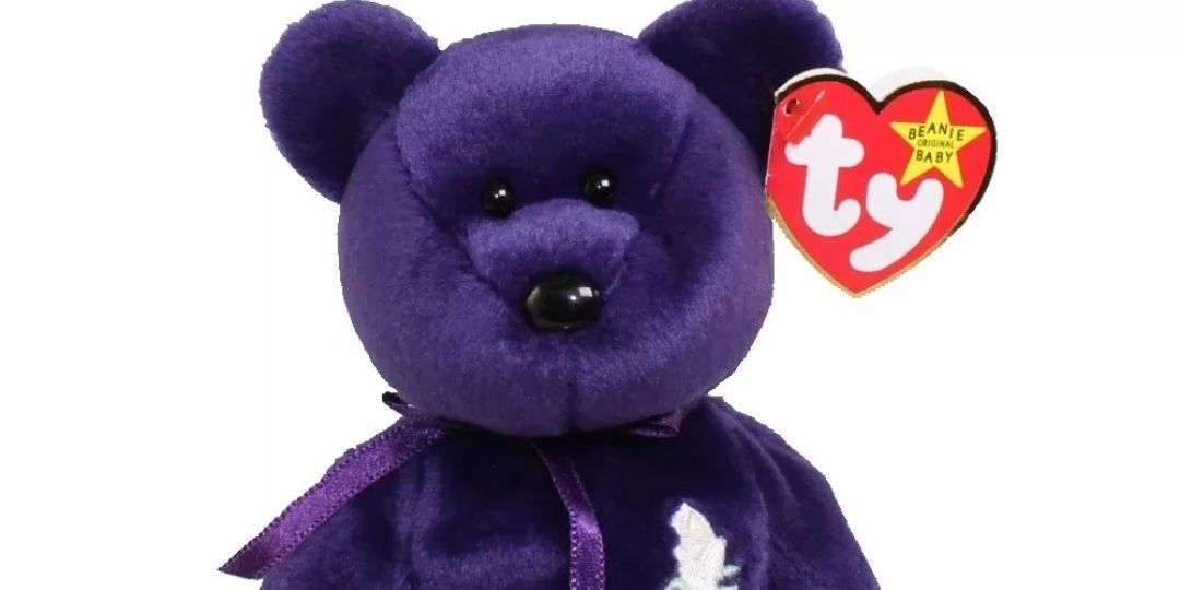 A purple teddy bear with a white lily sits on a white background