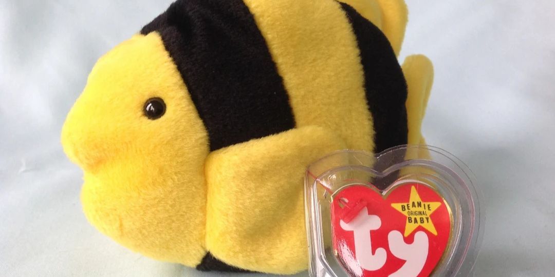 A yellow fish with black stripes sits on a desk
