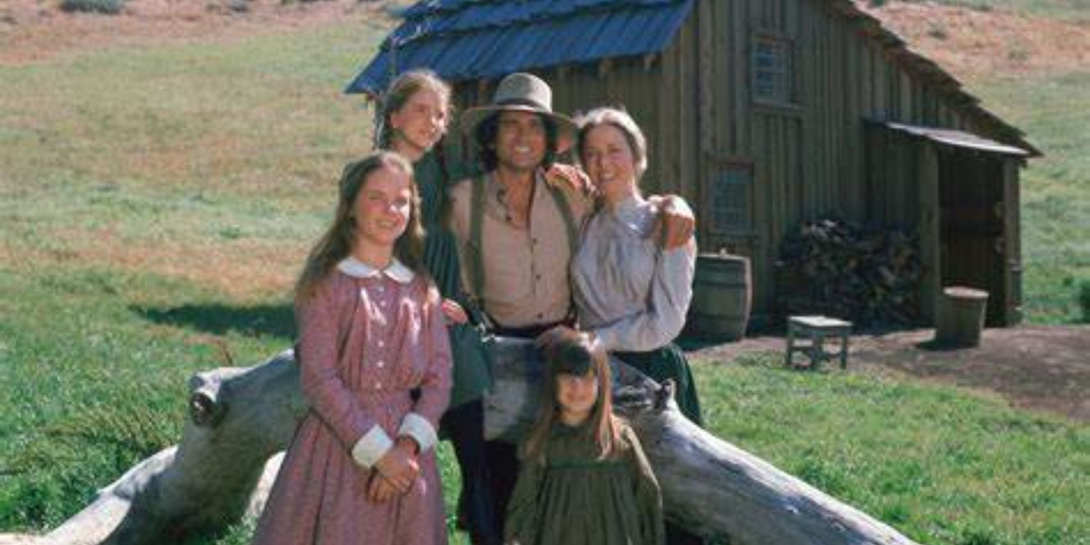 The family of Little House On The Prairie posing outside their small wooden home.