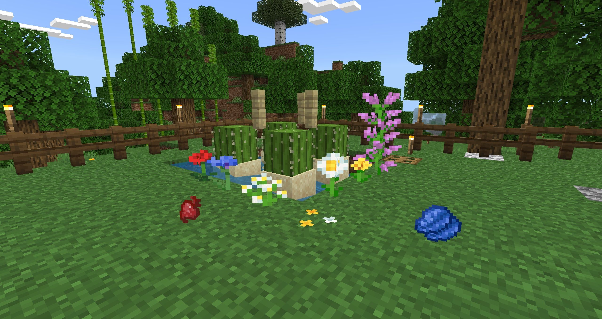 A bunch of common dye ingredients laid out around an automatic cactus farm, which include flowers,  lapis lazuli, and a beet, as well as the cactuses themselves in Minecraft.