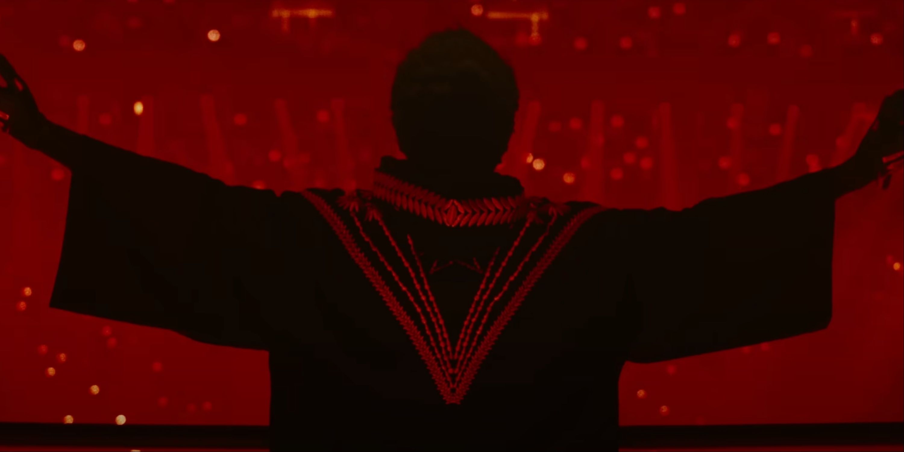 Abel coming onstage as The Weeknd before a massive live audience with arms raised and back towards the camera in Hurry Up Tomorrow.