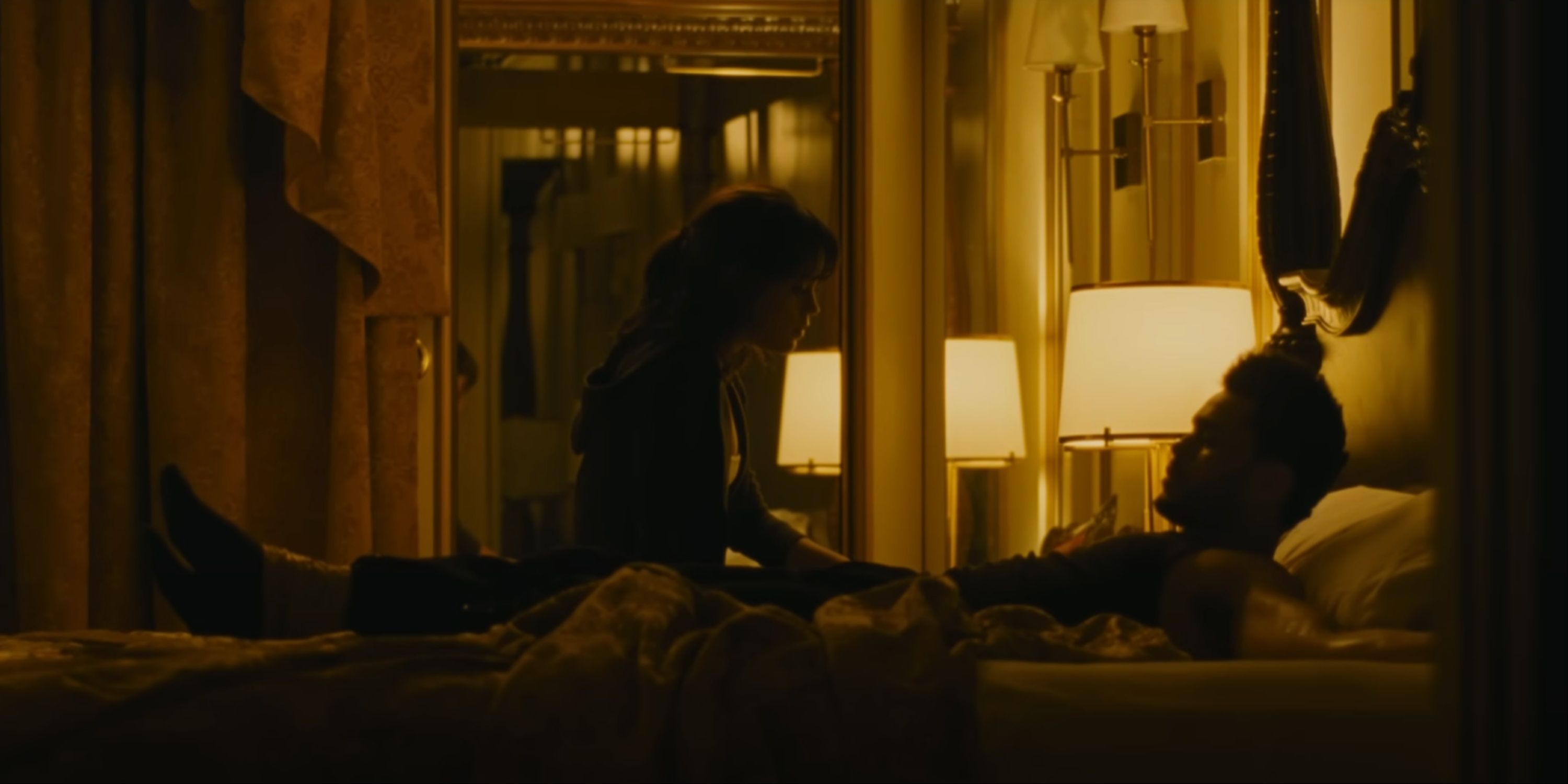 Jenna Ortega next to The Weeknd as he's tied to the bed in their hotel room in Hurry Up Tomorrow.