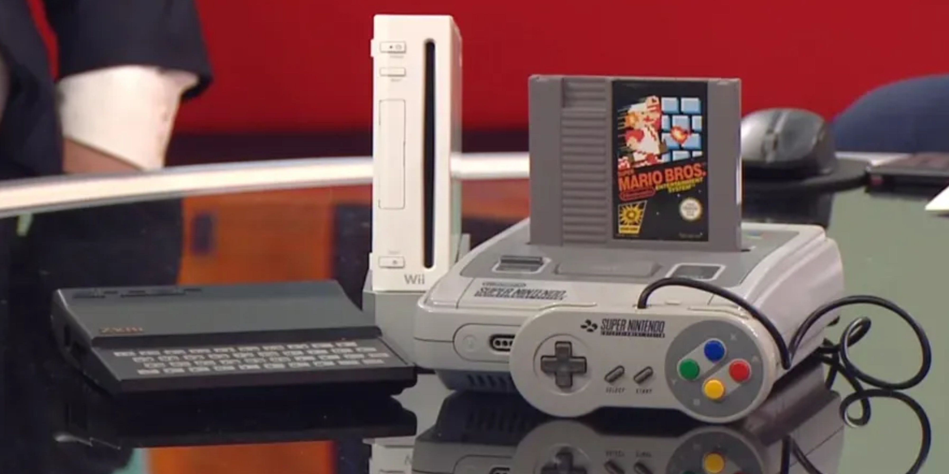a nintendo wii next to a snes with a nes cartridge in it.