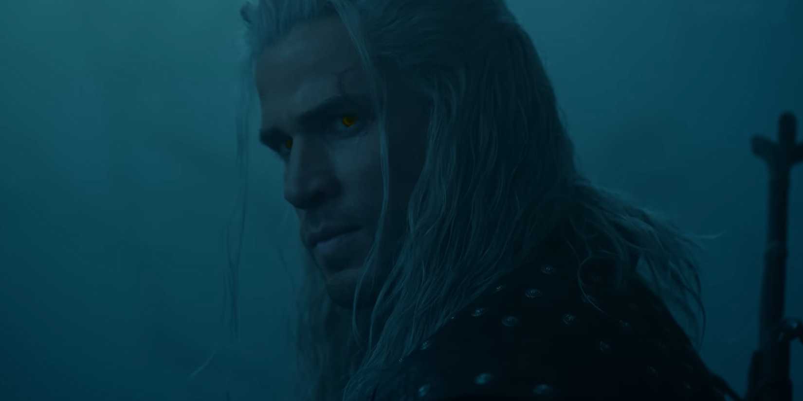 A man with long white hair is looking at his shoulder.