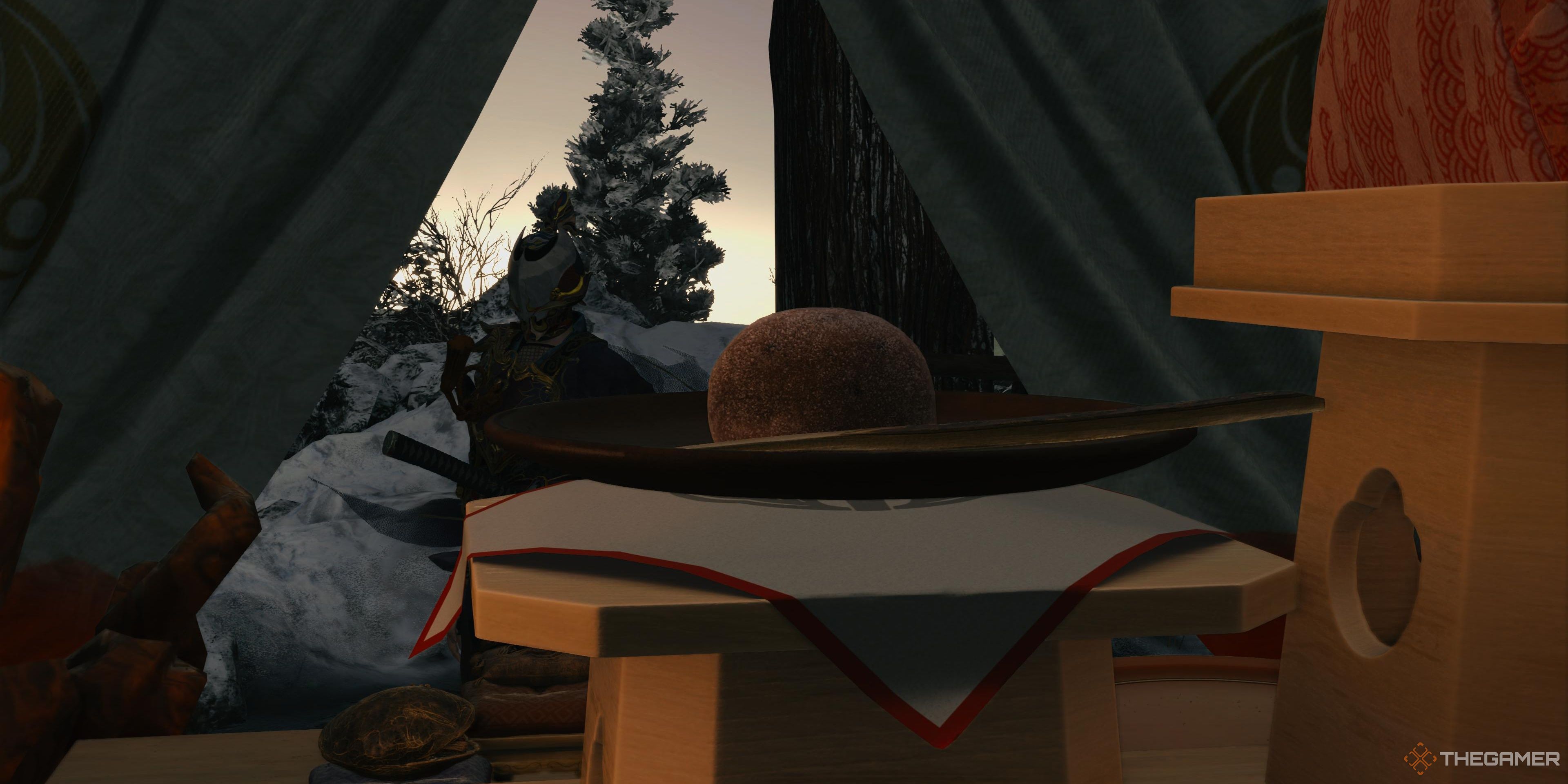 Soh looking at an Inoko Mochi sweet in Yoshiro's tent from Kunitsu-Gami: path of the goddess..