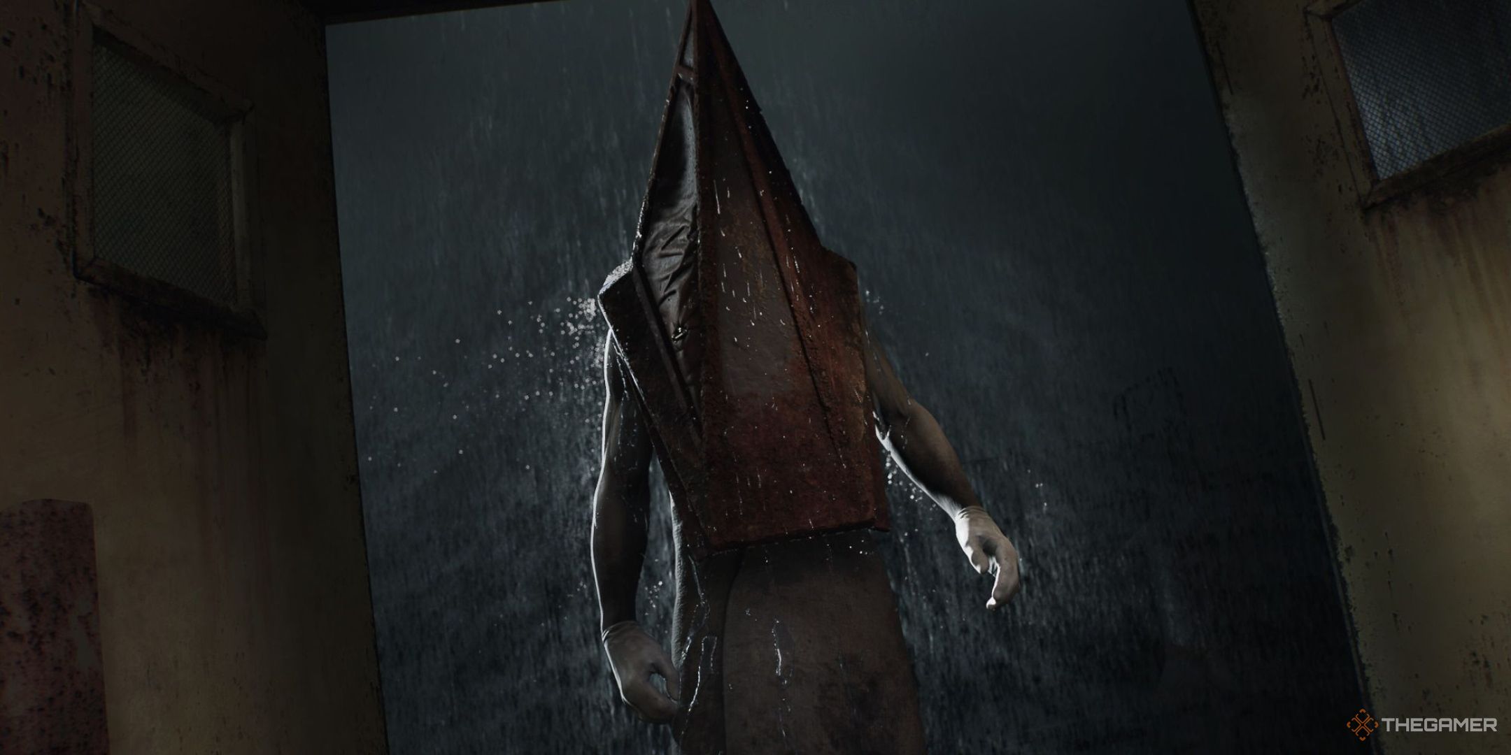 Pyramid Head stands in a rainy doorway in the Silent Hill 2 remake.