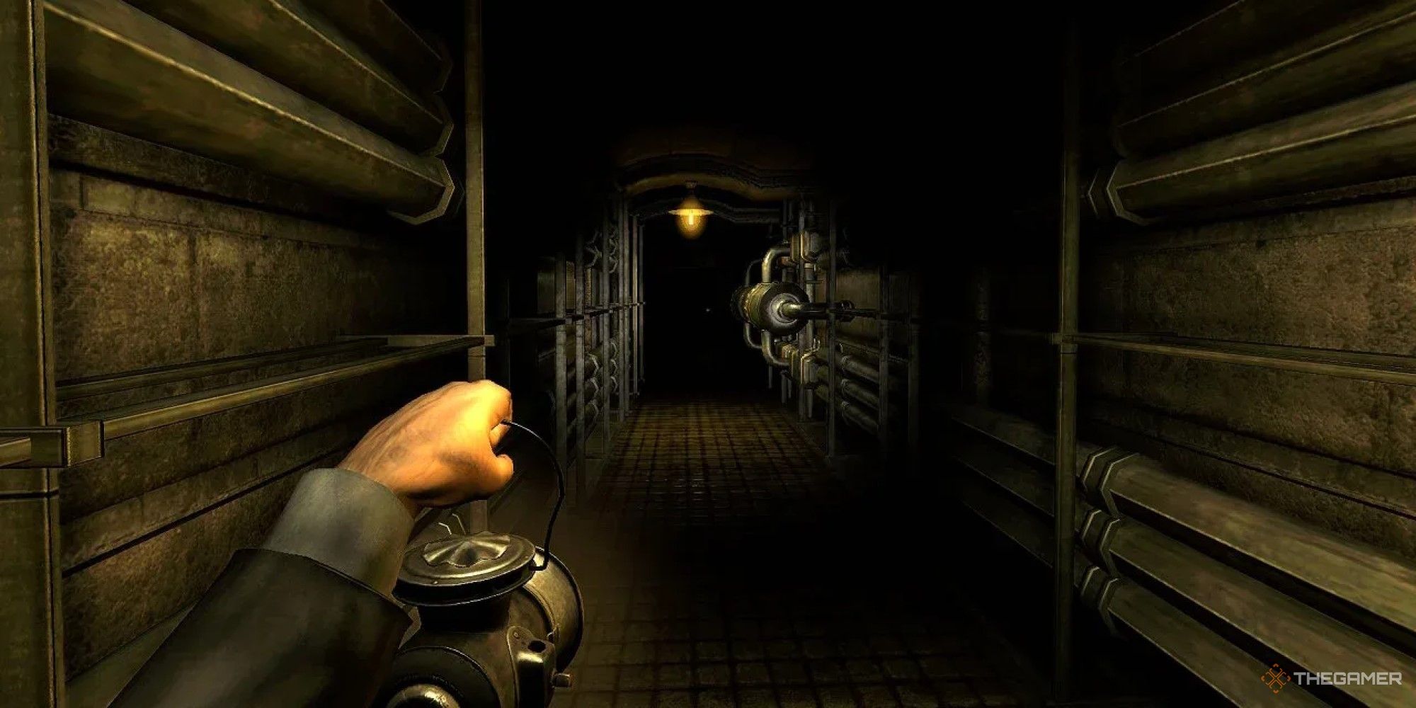 A screenshot from Amesia – A Machine For Pigs. A hand holds a lantern in a dark corridor with walls lined with pipes.