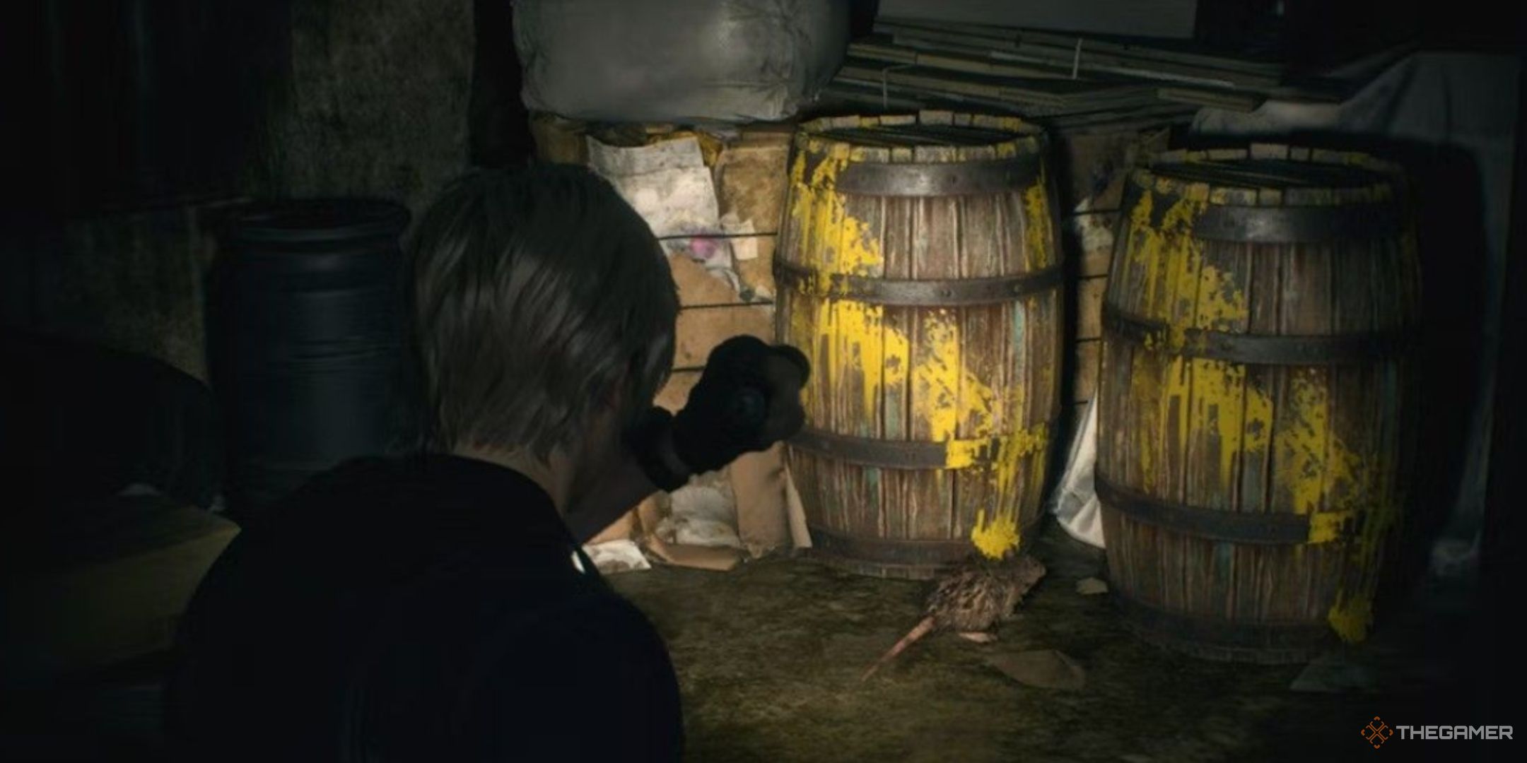 leon kennedy shines his flashlight on some barrels splattered with yellow paint, with a rat between them, in Resident Evil 4 Remake.