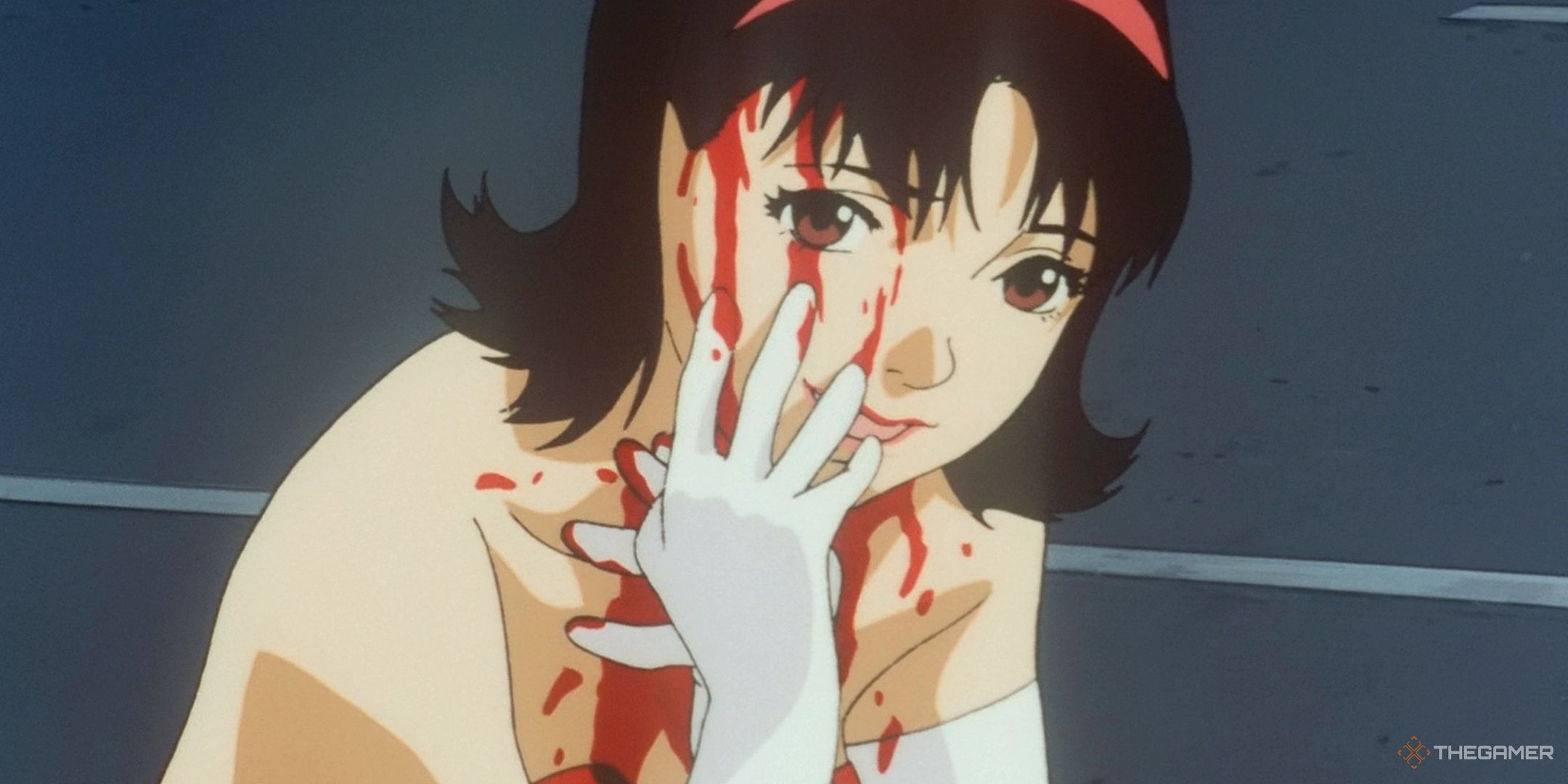 Pop Idol Mima dressed in white gloves and a red dress wipes blood down the side of her face while smiling at the camera.