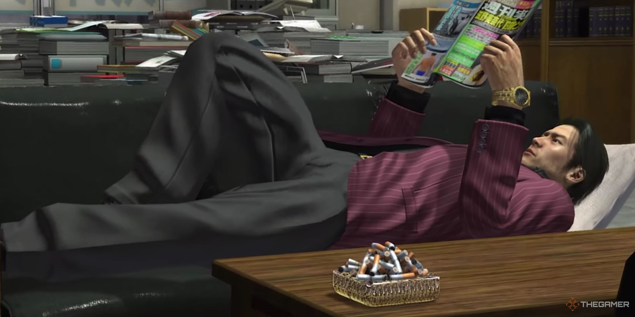 Shun Akiyama is reading a a magazine while lying on a couch. 