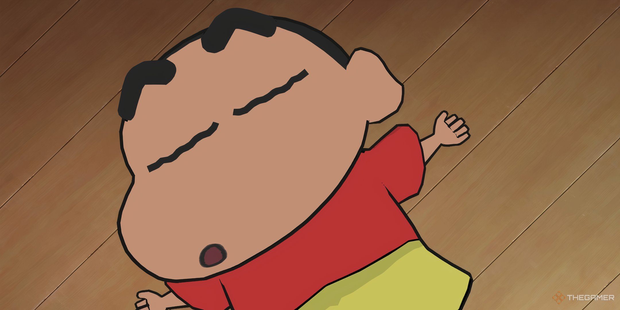Shin-Chan napping on the wooden floor of his home in Shin-Chan: Shiro And The Coal Town.