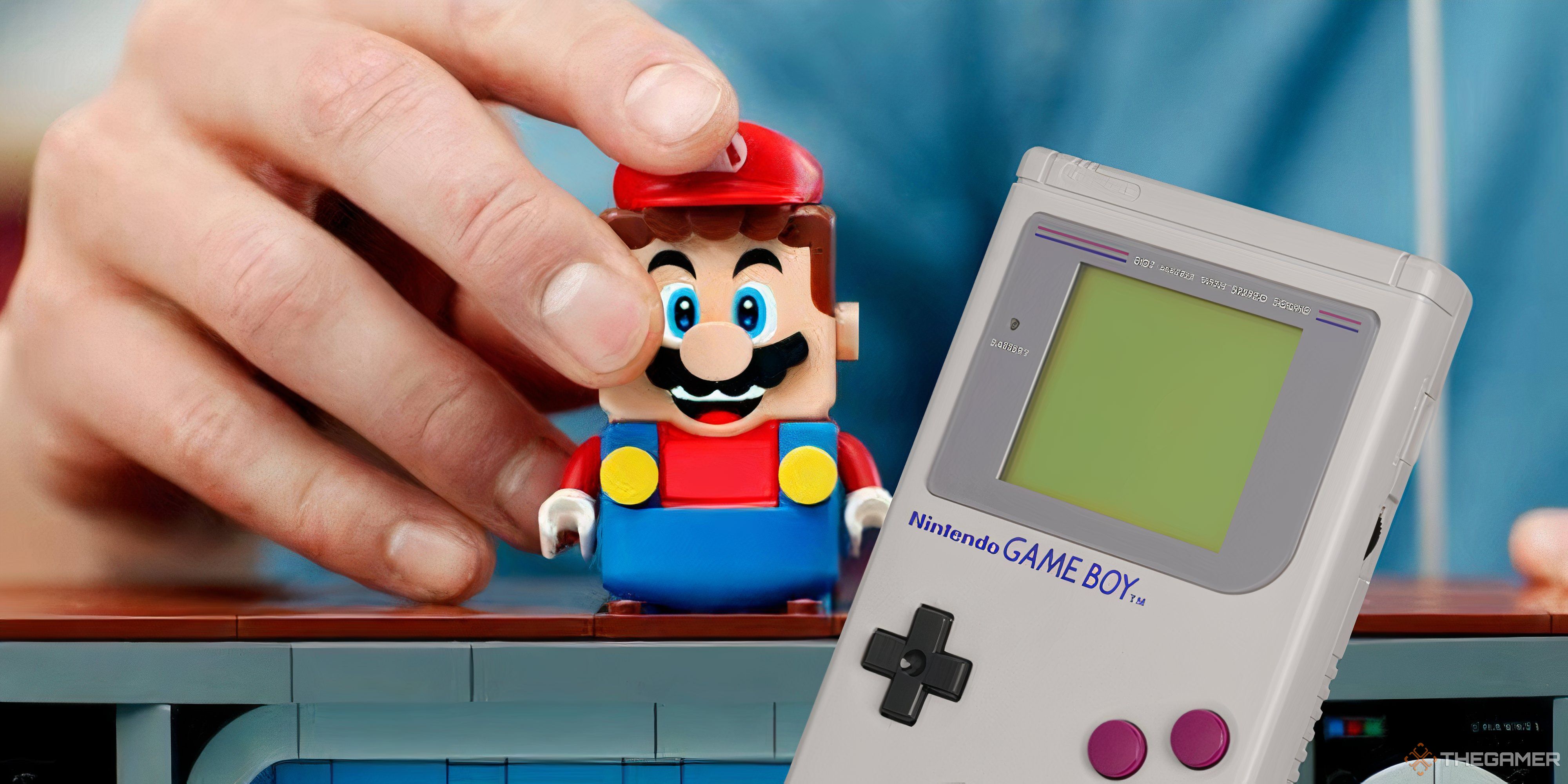 someone holding a lego mario figure next to a game boy.