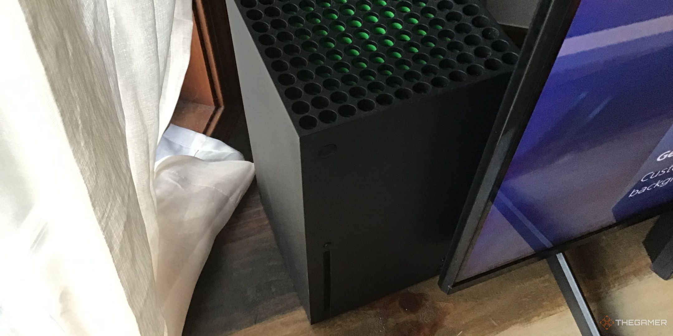 A standing Xbox Series X console next to a TV.
