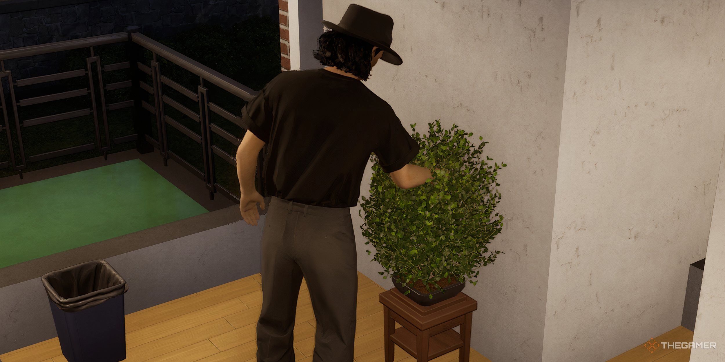 A man pruning a bonsai tree in his home by a trash can.