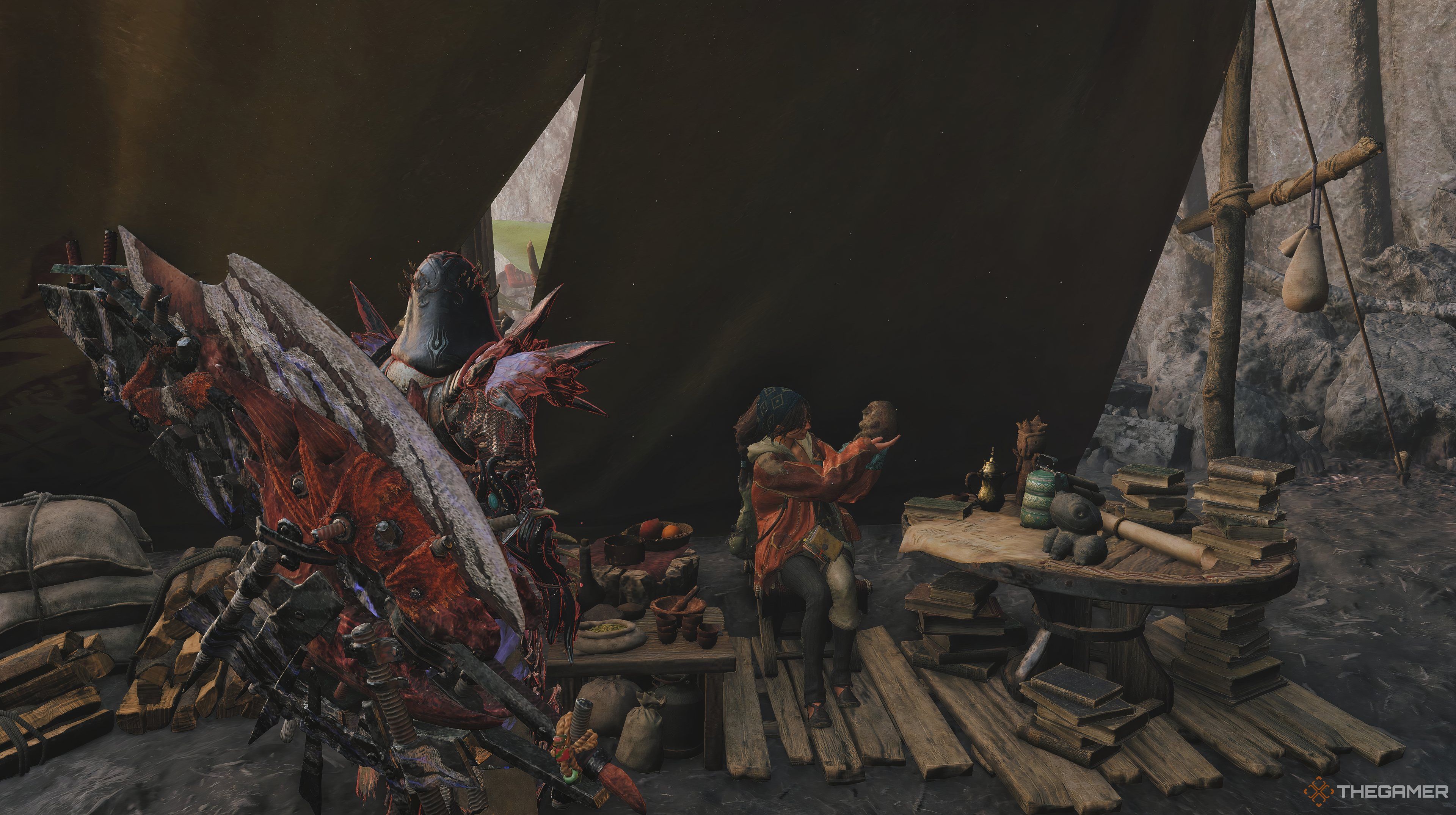 Monster Hunter Wilds character looking at Alma who holding a small object. There is an assortment of items around her with a tabel to her right. 