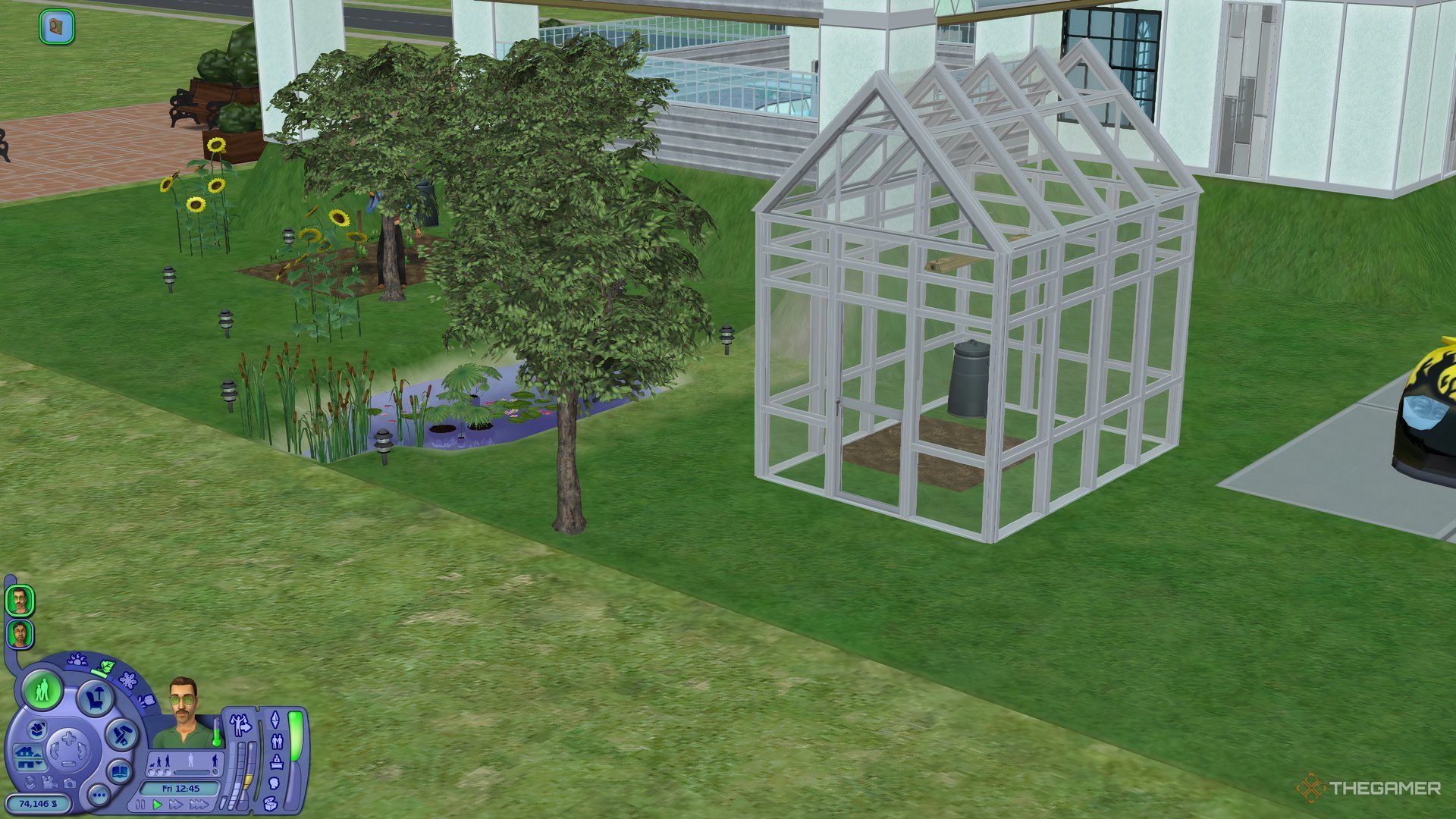 A greenhouse stood next to a pond, car, and fruit trees in The Sims 2.