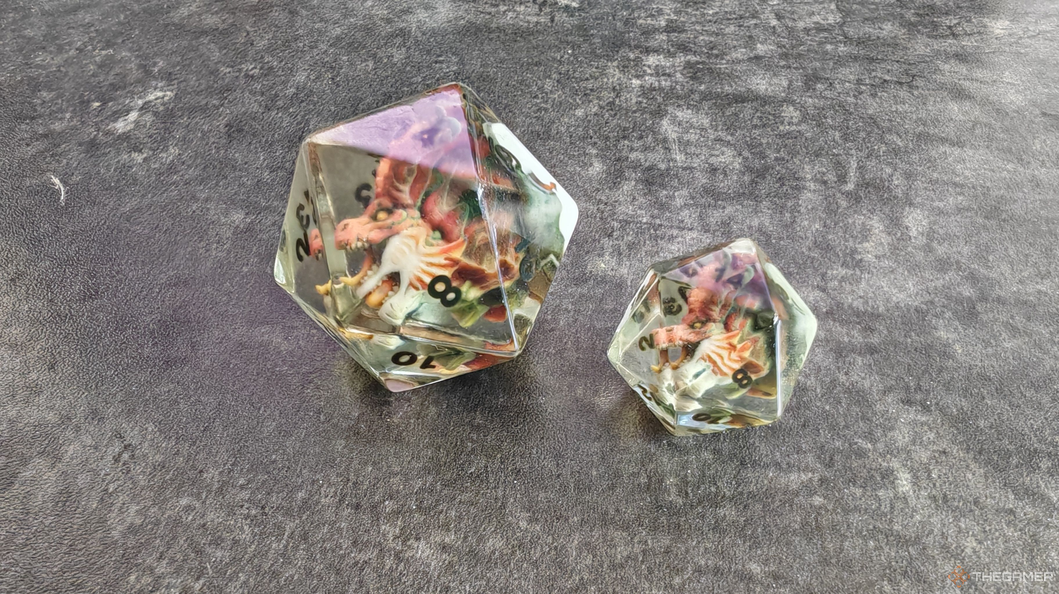 Two clear d20 dice with dragon heads inside them