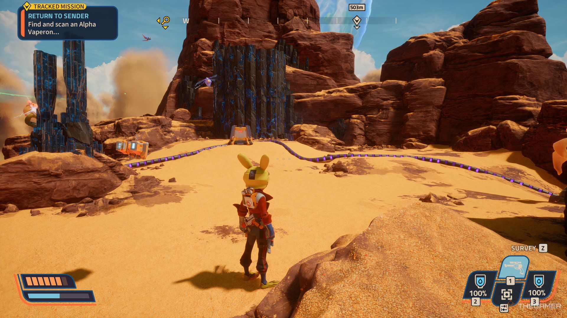 Player looking at a crate with a black and blue block behind it in Revenge of the Savage Planet. There are two purples cables attached to it.